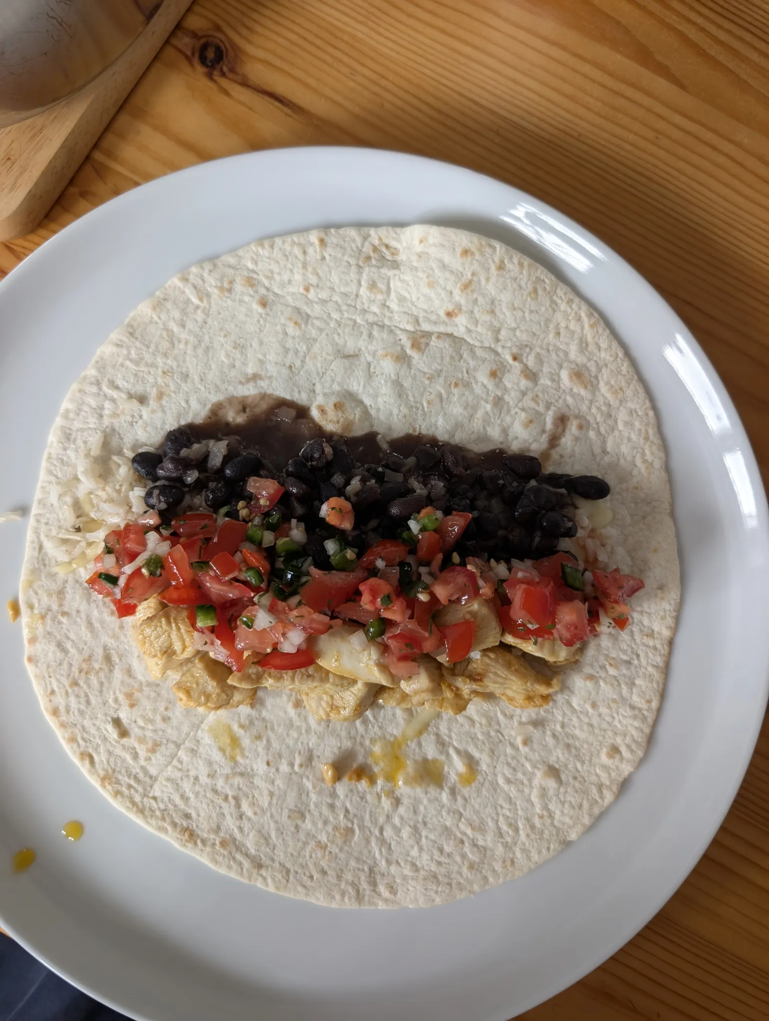 Burrito füllen: Auf den geschmolzenen Käse zuerst Bohnen (je ca. 1/3 Tasse), dann Reis (ca. 1/4 Tasse), Hähnchenstreifen, anschließend Pico de Gallo und Mexikanische Salsa geben.